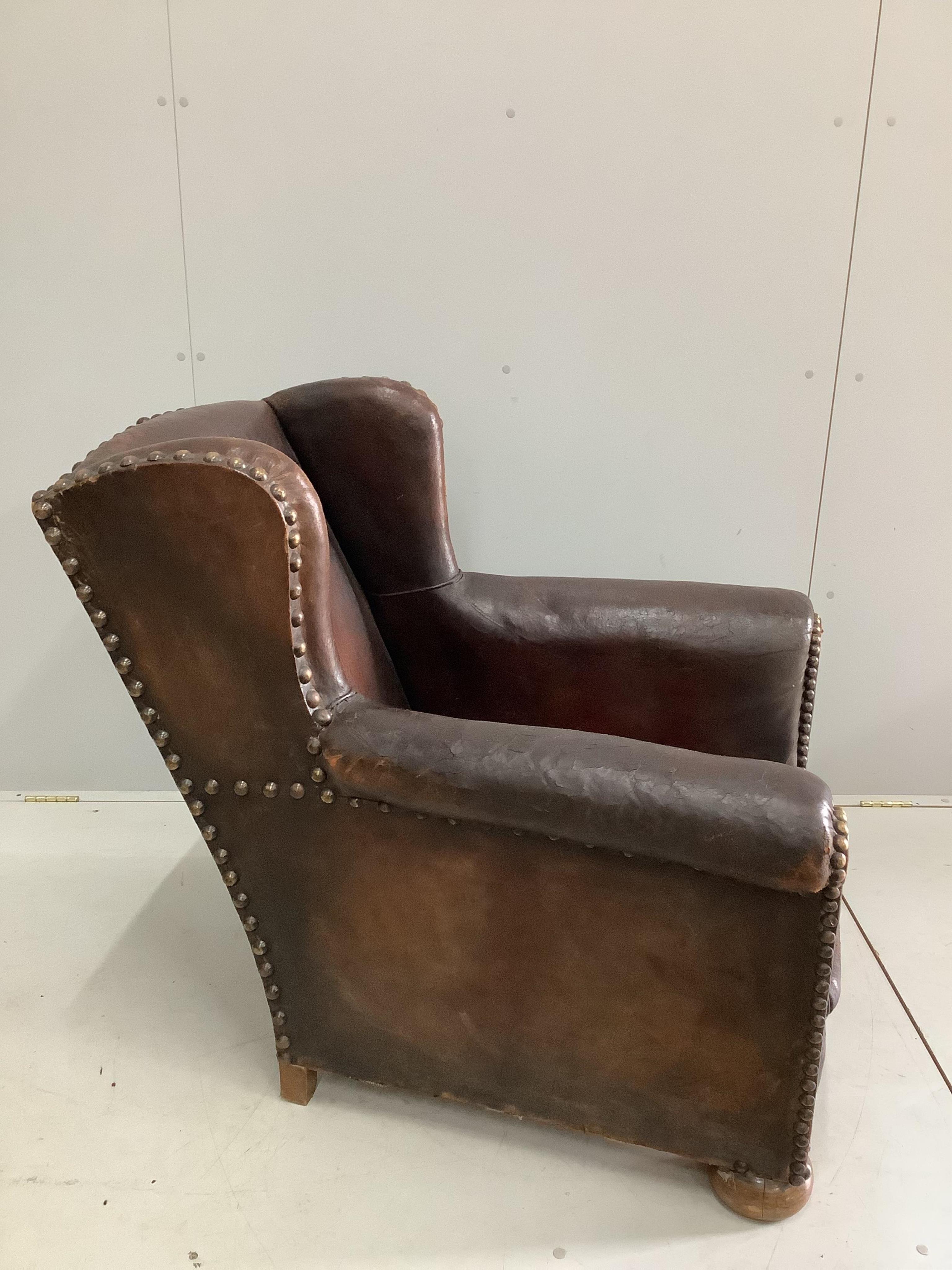 An early 20th century studded tan leather club armchair, width 84cm, depth 90cm, height 92cm. Condition - fair